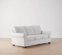 a white couch sitting on top of a hard wood floor next to a white wall