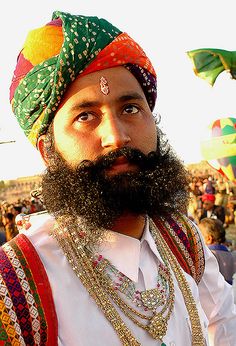 a man with a long beard wearing a colorful turban and beads on his head