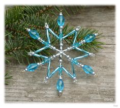 a snowflake ornament hanging from a pine tree on a wooden table