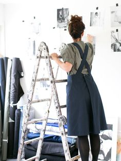 a woman standing on a ladder in front of a wall