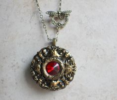 "Red rivoli crystal music box pendant. This round music box pendant is inspired by the gorgeous music box pendants of era's gone by. Music box is pill box size, please look at the dimensions for exact size. A perfect round bronze locket has been adorned with layers of bronze filigree and Red Rivoli Crystal in the center. The bronze filigree layers have been sealed in a clear resin to give a glass like finish and preserve the beauty of this musical pendant. The music box winds from a key on the b Music Box Necklace, Music Box Locket, Box Necklace, Music Box Jewelry, Gothic Accessories, Necklace Box, Red Crystals, Clear Resin, Locket Necklace