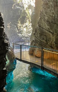 a man is standing on a bridge over a pool in the middle of a canyon