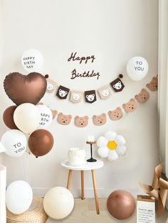 a birthday party set up with balloons and teddy bears on the wall, including cake