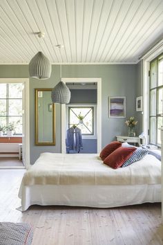 a white bed sitting in a bedroom next to two windows