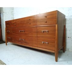 a large wooden dresser sitting on top of a white floor next to a brick wall