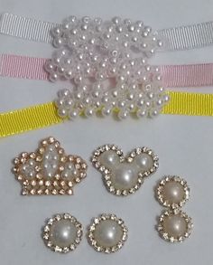 several different types of pearls and bows on a white surface with yellow ribbon around them