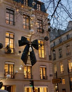 a large black bow hanging from the side of a building next to a street light