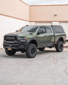 a large green truck parked in front of a building