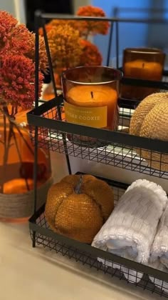 three tiered trays holding candles, towels and pumpkins on a counter top