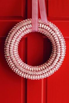 a white wreath hanging on a red door