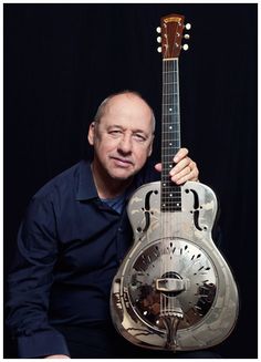 a man is holding an old style guitar