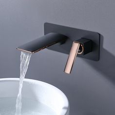 a faucet with water running from it in a white bowl next to a gray wall