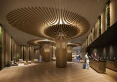 people are walking around in the lobby of an office building with wooden columns and circular ceilinging