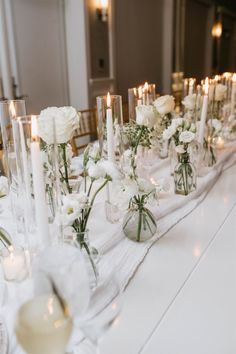 a long table with candles and flowers in vases on it's centerpiece