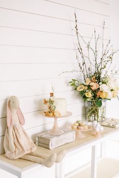 a table topped with a cake next to a vase filled with flowers and other items