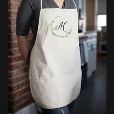 a woman wearing an apron with the letter m on it and a monogrammed wreath