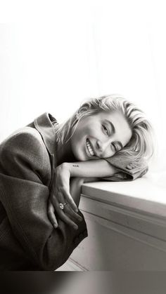 a black and white photo of a woman leaning on a window sill