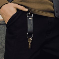 a person wearing black pants and holding a keychain in their pocket with the word,