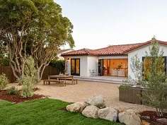 a backyard with a table and chairs in the grass next to some rocks on the ground