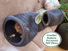 a cat in a crochet pet tunnel on a couch