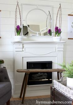 a living room with a fireplace, mirror and table in front of the fire place