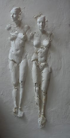 two white sculptures are on the wall next to each other