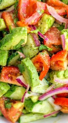 a salad with tomatoes, avocado and red onion on it in a white bowl