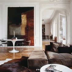 a living room filled with furniture and a painting on the wall next to a table