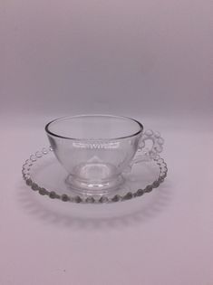 an empty glass cup and saucer on a white table top with beads around the rim