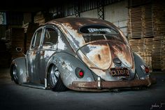 an old vw bug sitting in a garage with rust on it's paint