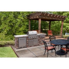 an outdoor kitchen with grill, table and chairs