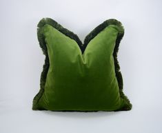 a green pillow with fringe edges on a white background