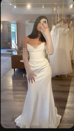 a woman in a white dress taking a selfie