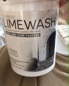 a person holding up a white cup that says limewash on the inside of it