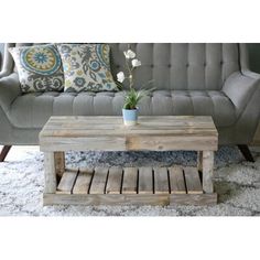 a living room with a couch, coffee table and rug on the floor in front of it