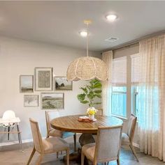 a dining room table with chairs and pictures on the wall