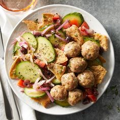 a white plate topped with meatballs and veggies next to a glass of wine