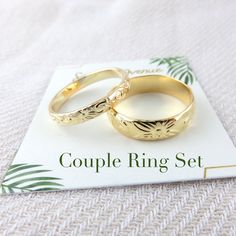 two gold wedding rings sitting on top of a white card that says couple ring set