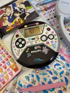 an electronic device sitting on top of a table covered in stickers and other items