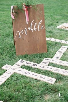 wooden scrabble tiles laid out on the grass to spell words for wedding guests