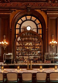 a bar with many bottles on the shelves and lights hanging from the ceiling above it