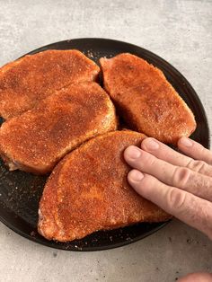 three pieces of fried meat on a plate being held by a person's hand