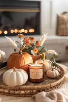 pumpkins, flowers and candles on a tray in front of a fire place setting