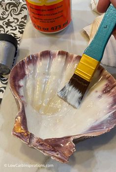 a person holding a paint brush in an oyster shell