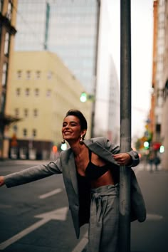 a woman leaning against a pole on the street