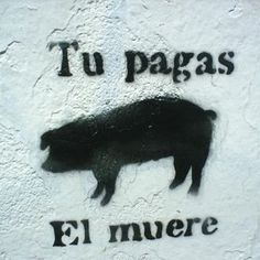 a black pig painted on the side of a building with spanish words written below it