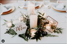 a table topped with candles and greenery