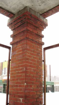 a red brick fire hydrant in front of a window with snow on the ground