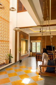 a woman is sitting on a swing in the middle of a room with yellow and white flooring