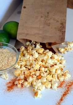 a bag full of popcorn next to some limes and seasoning on a table